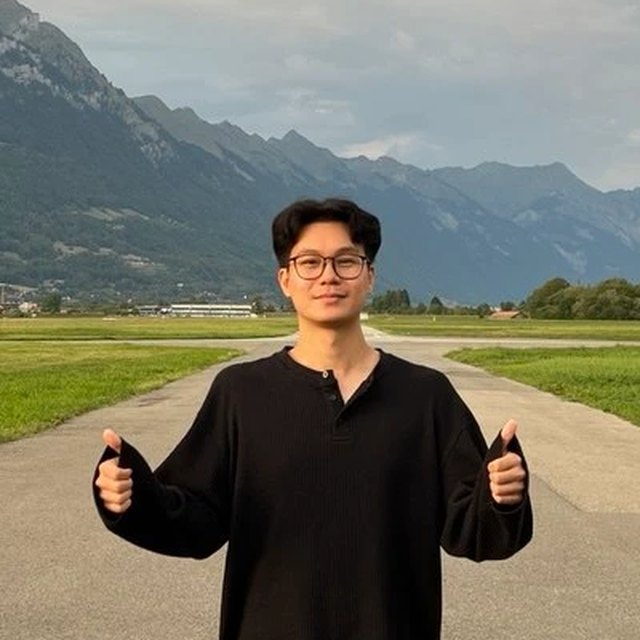 Max, the tutor, giving two thumbs up on an airfield in front of mountains